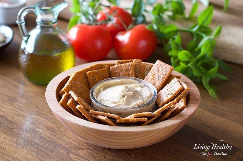 a bowl of cassava flour crackers with a small serving dish of hummus dip in the center